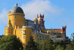 Exterior view of Pena Palace in Sintra with a blue sky and green trees.